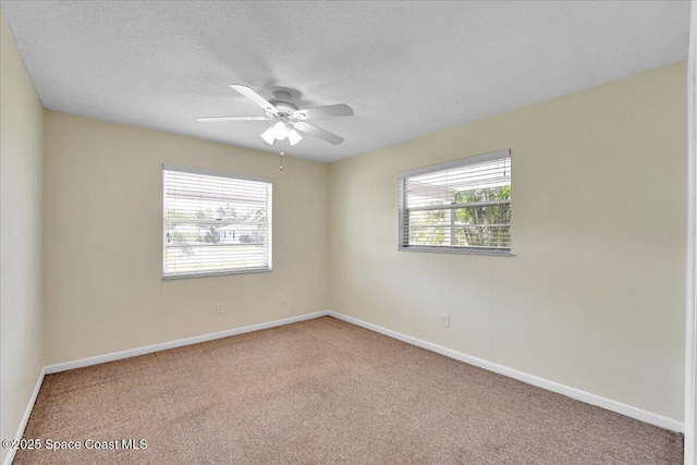 carpeted spare room with ceiling fan, a healthy amount of sunlight, and a textured ceiling