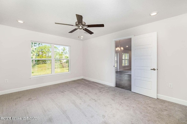 spare room with ceiling fan with notable chandelier, carpet, and a textured ceiling