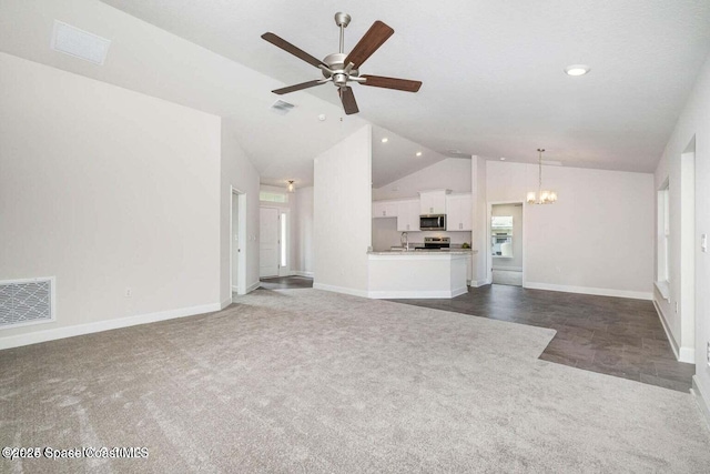 unfurnished living room with sink, ceiling fan with notable chandelier, high vaulted ceiling, and dark colored carpet