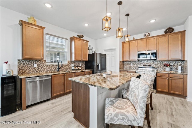 kitchen featuring a breakfast bar, light stone counters, a center island, pendant lighting, and stainless steel appliances