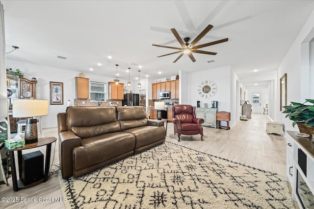 living room with ceiling fan and light hardwood / wood-style flooring