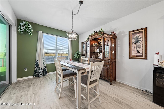 dining space with light hardwood / wood-style floors and a chandelier