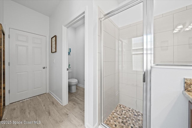 bathroom featuring hardwood / wood-style flooring, vanity, toilet, and a shower with shower door