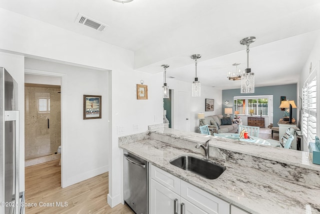 kitchen featuring decorative light fixtures, dishwasher, white cabinetry, sink, and light stone countertops