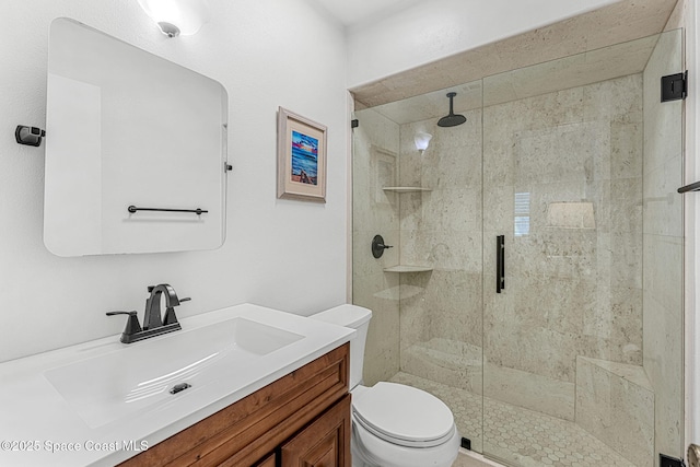 bathroom with vanity, a shower with door, and toilet