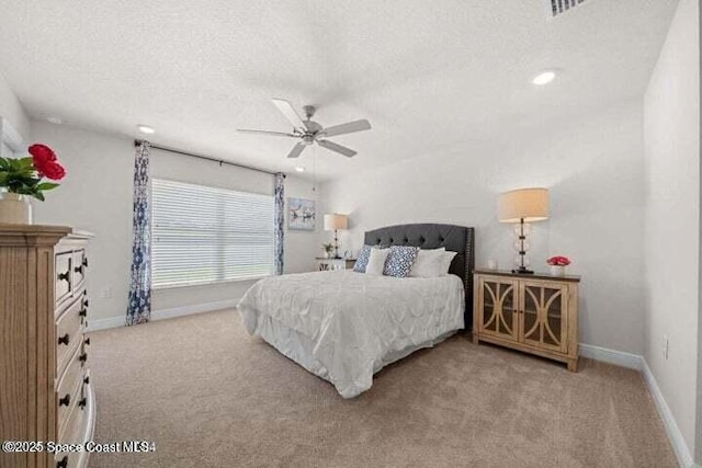 bedroom featuring ceiling fan, light colored carpet, and a textured ceiling