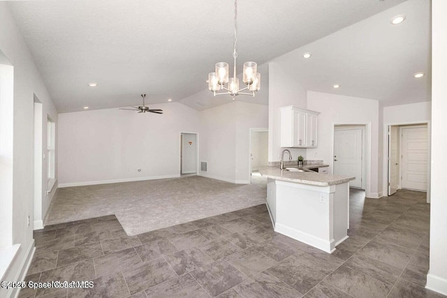 kitchen with white cabinets, vaulted ceiling, a sink, a peninsula, and ceiling fan with notable chandelier