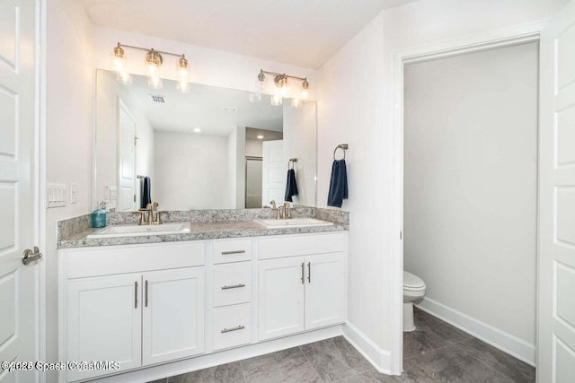 full bath featuring double vanity, a sink, toilet, and baseboards