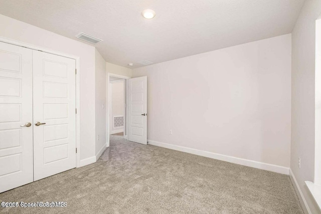 unfurnished bedroom featuring carpet floors, baseboards, visible vents, and a closet