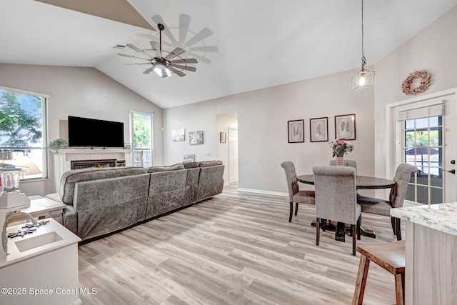 living room with a healthy amount of sunlight, light wood-style flooring, ceiling fan, and vaulted ceiling