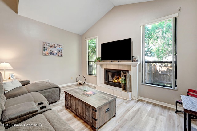 living room with a fireplace, baseboards, light wood-type flooring, and lofted ceiling