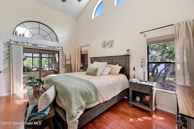 bedroom featuring access to outside, multiple windows, and wood finished floors