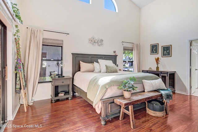 bedroom featuring a high ceiling, baseboards, and wood finished floors