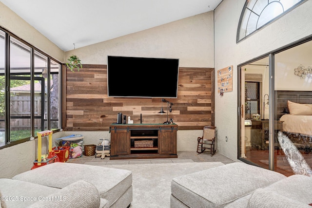 living area with wooden walls, high vaulted ceiling, and a textured wall