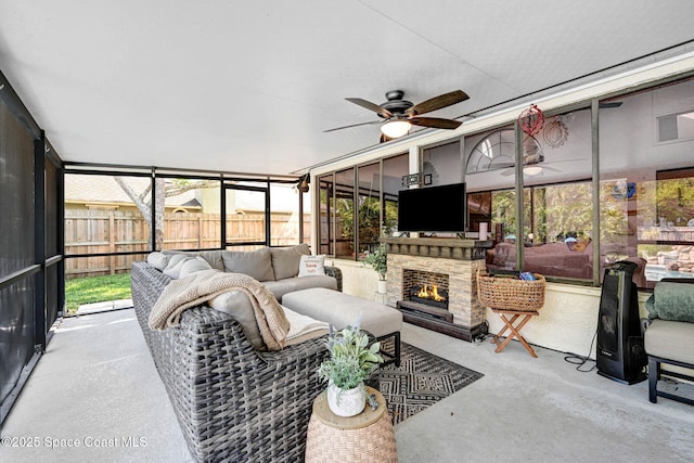 sunroom with an outdoor stone fireplace and ceiling fan