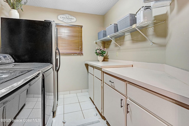 clothes washing area featuring baseboards, light tile patterned floors, cabinet space, independent washer and dryer, and a textured ceiling