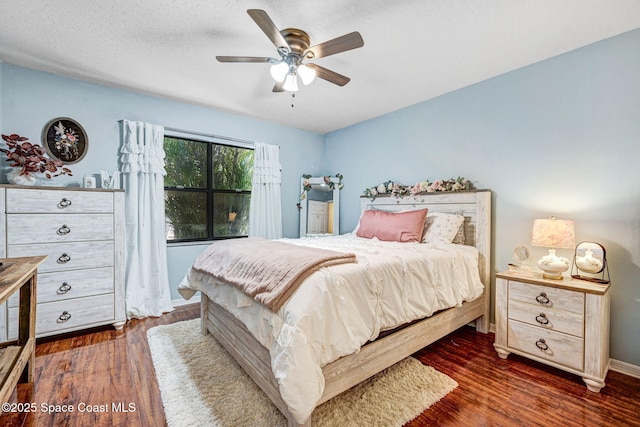 bedroom with baseboards, a ceiling fan, dark wood-style flooring, and a textured ceiling