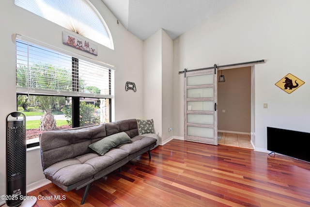 living area featuring baseboards, lofted ceiling, a barn door, and wood finished floors