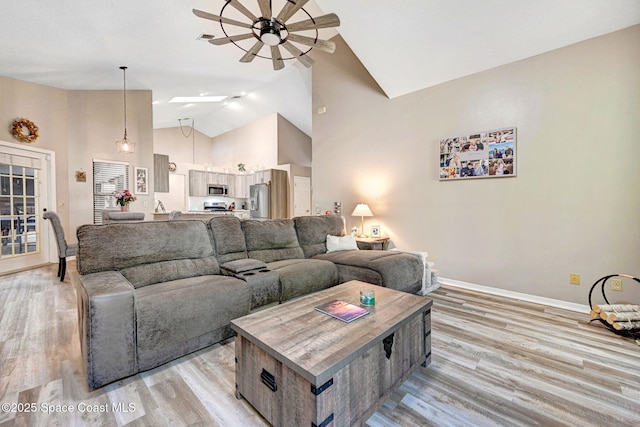 living room featuring visible vents, baseboards, high vaulted ceiling, ceiling fan, and light wood-type flooring