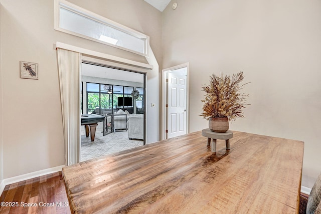 hall with baseboards, a towering ceiling, and wood finished floors