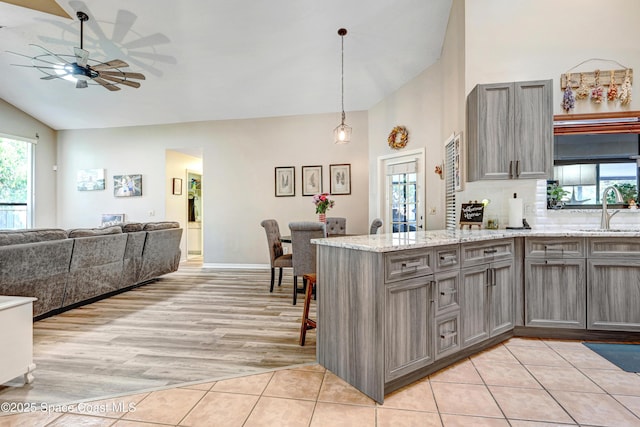 kitchen with a ceiling fan, a peninsula, light tile patterned flooring, gray cabinets, and a sink