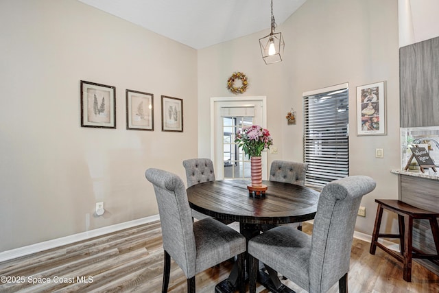 dining room with light wood-style flooring, baseboards, and vaulted ceiling