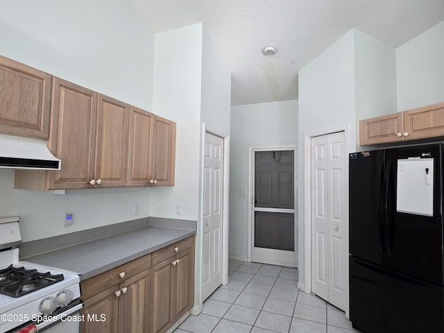 kitchen featuring black fridge, white gas range oven, and light tile patterned floors