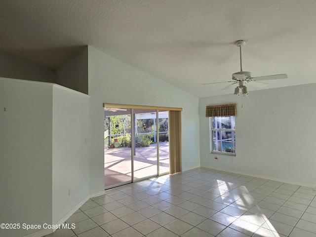 empty room featuring lofted ceiling, a wealth of natural light, a textured ceiling, and light tile patterned flooring