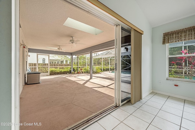 interior space with lofted ceiling with skylight, a wealth of natural light, and ceiling fan