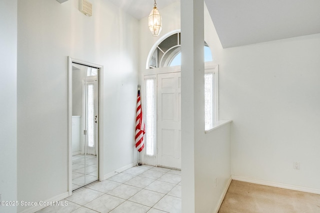 entryway with a high ceiling, light tile patterned floors, and a chandelier