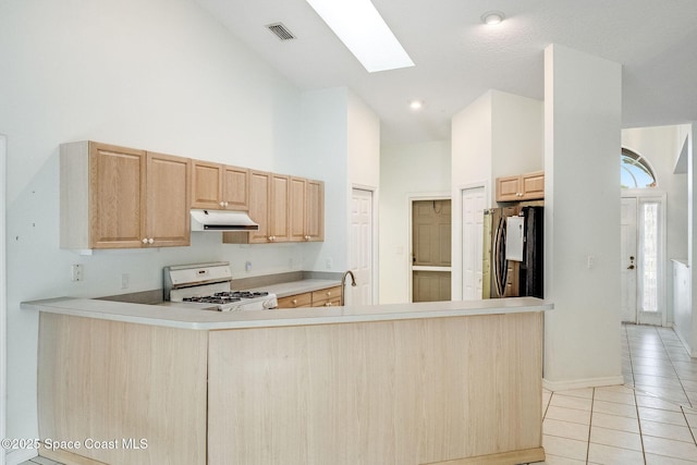 kitchen featuring high vaulted ceiling, light brown cabinetry, white range, kitchen peninsula, and black fridge