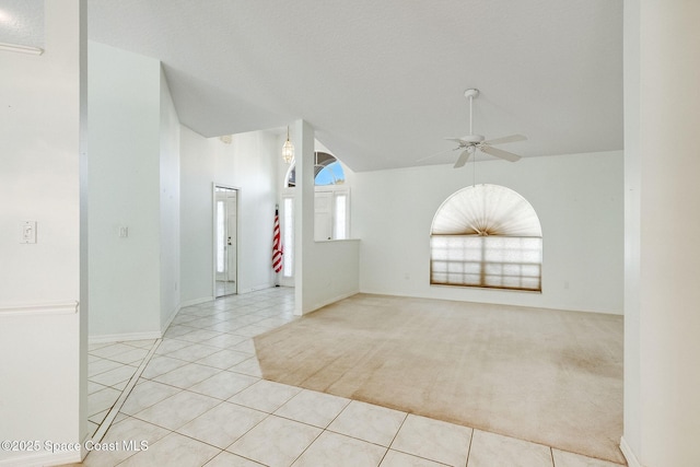 tiled empty room featuring vaulted ceiling and ceiling fan