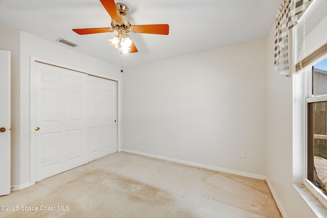 unfurnished bedroom featuring ceiling fan, light colored carpet, and a closet