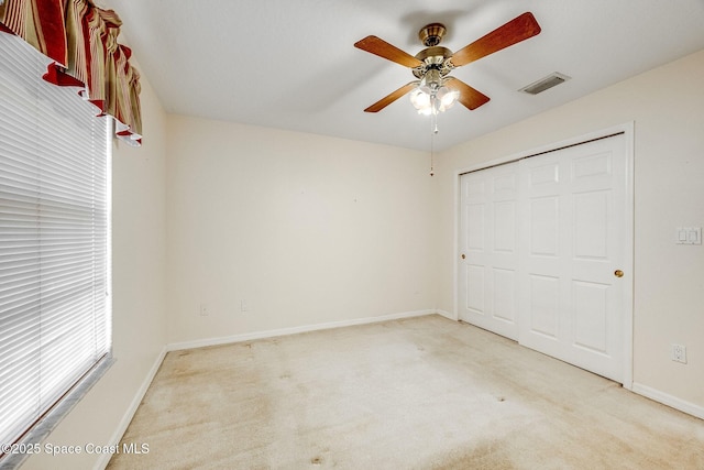 unfurnished bedroom with light colored carpet, ceiling fan, and a closet