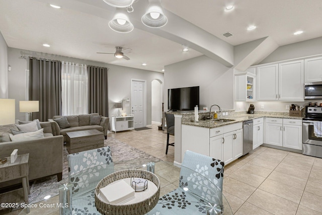 kitchen with white cabinetry, stone countertops, light tile patterned floors, appliances with stainless steel finishes, and kitchen peninsula