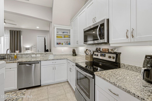 kitchen featuring sink, light stone counters, light tile patterned floors, stainless steel appliances, and white cabinets