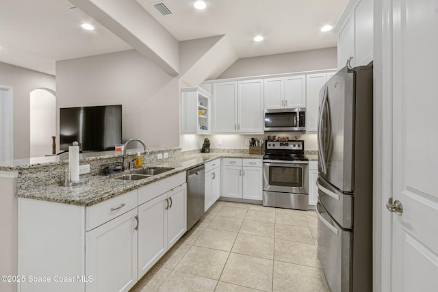 kitchen with appliances with stainless steel finishes, white cabinetry, sink, light stone counters, and kitchen peninsula