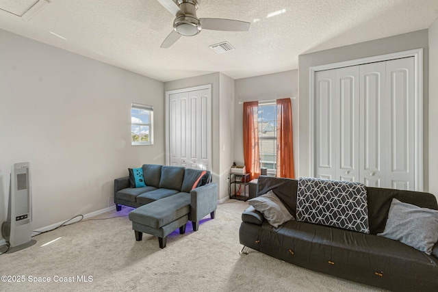 carpeted living room featuring a textured ceiling and ceiling fan