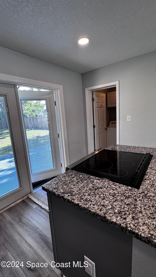 kitchen with dark hardwood / wood-style flooring, dark stone counters, and a textured ceiling