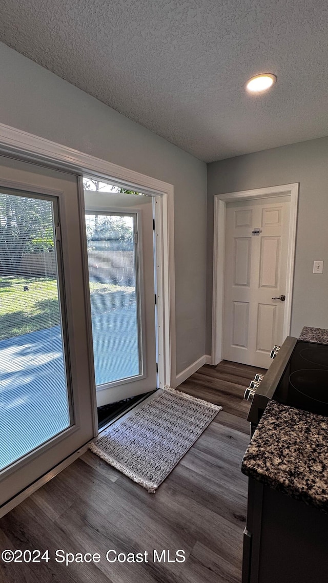 doorway with dark hardwood / wood-style floors and a textured ceiling