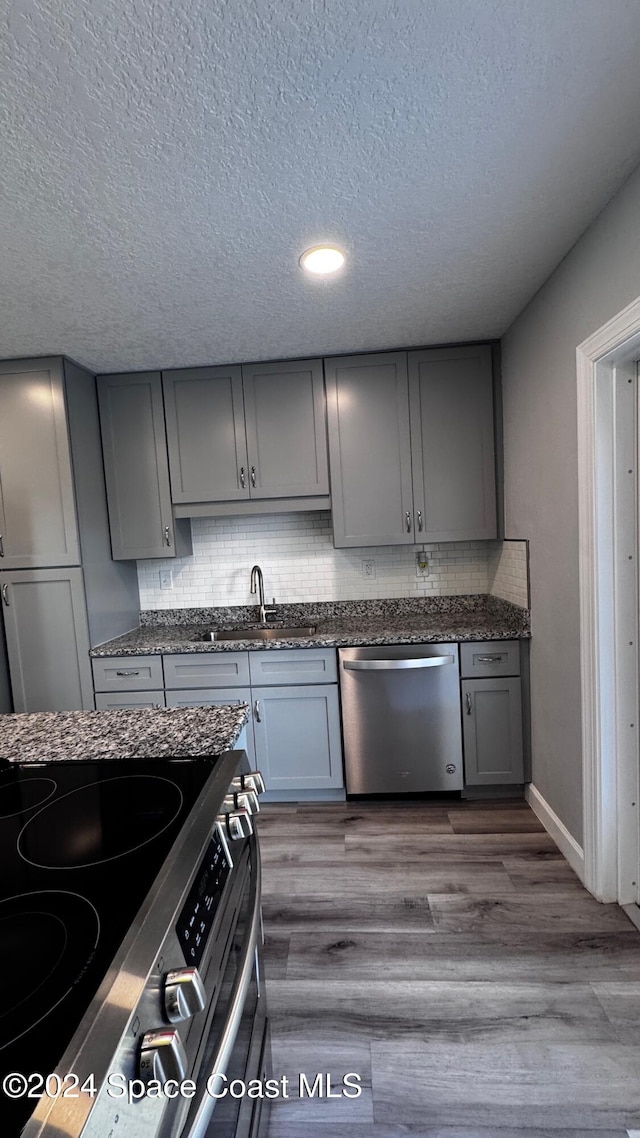 kitchen featuring hardwood / wood-style flooring, appliances with stainless steel finishes, sink, and decorative backsplash