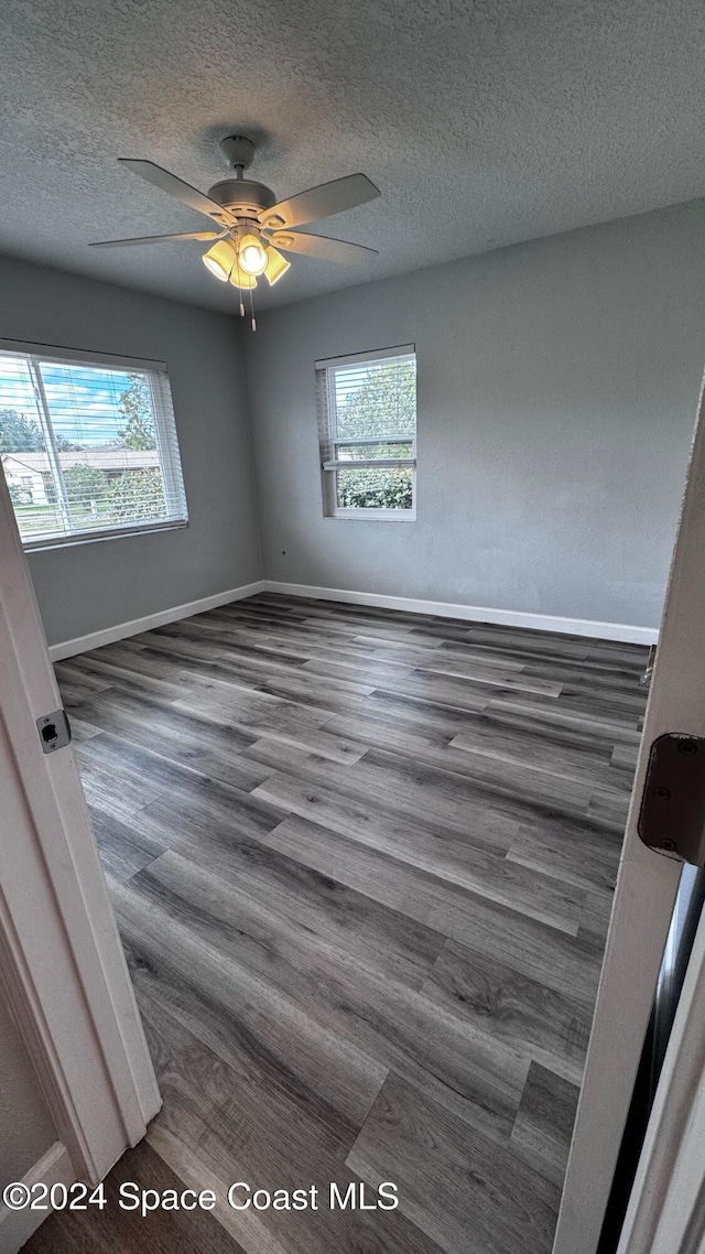 spare room with ceiling fan, a textured ceiling, and dark hardwood / wood-style flooring