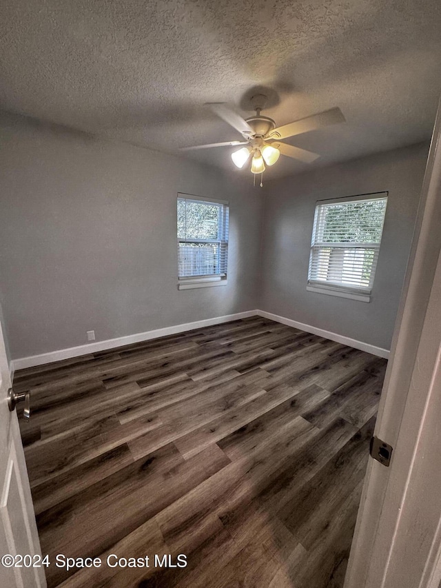 unfurnished room featuring ceiling fan, a healthy amount of sunlight, dark hardwood / wood-style flooring, and a textured ceiling