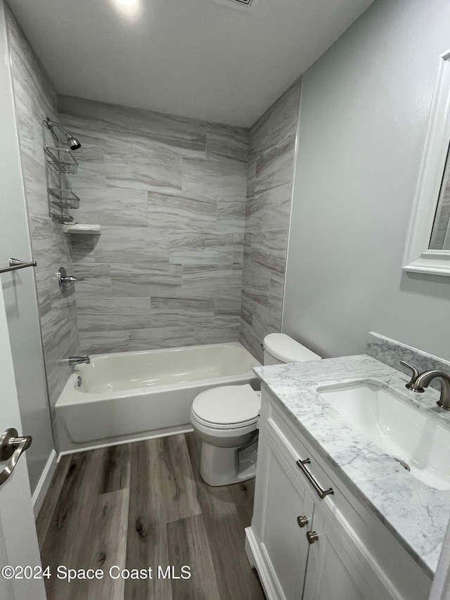 full bathroom featuring vanity, toilet, tiled shower / bath combo, and hardwood / wood-style floors