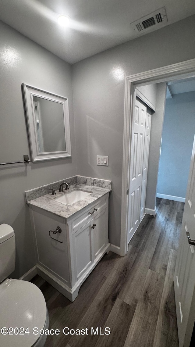 bathroom with wood-type flooring, toilet, and vanity