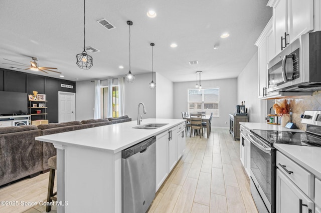 kitchen with pendant lighting, white cabinetry, an island with sink, sink, and stainless steel appliances