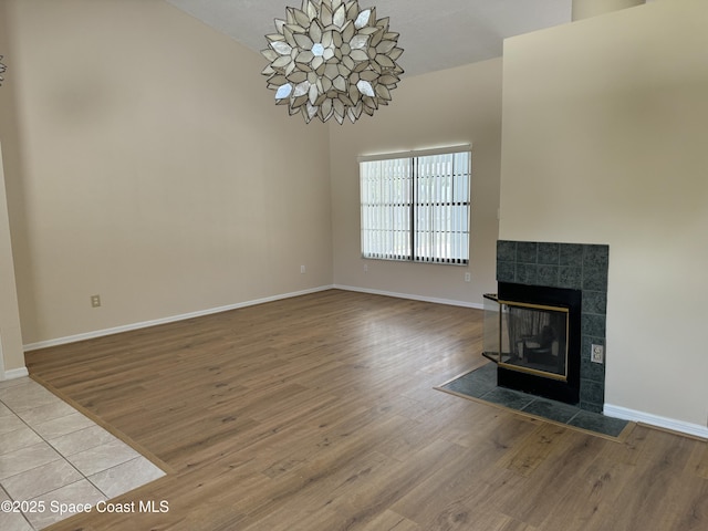 unfurnished living room featuring a tiled fireplace and hardwood / wood-style flooring