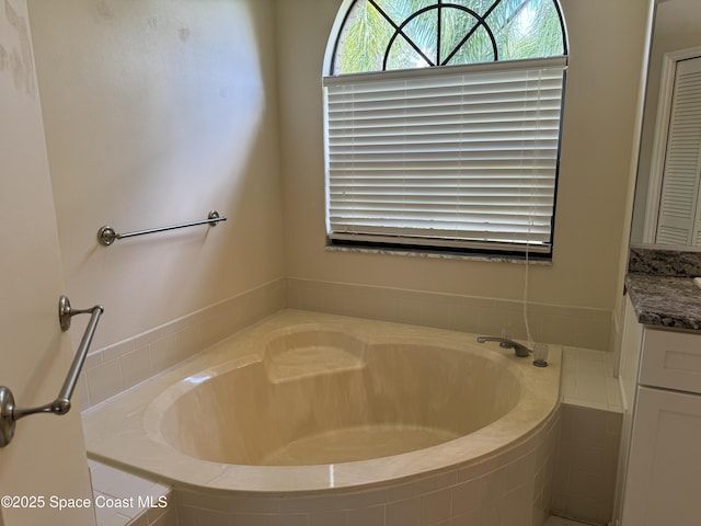 bathroom with vanity and tiled bath