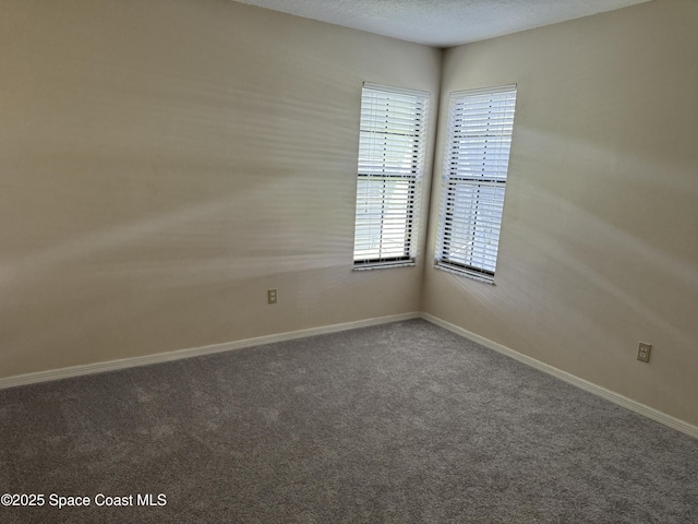 empty room with dark carpet and a textured ceiling