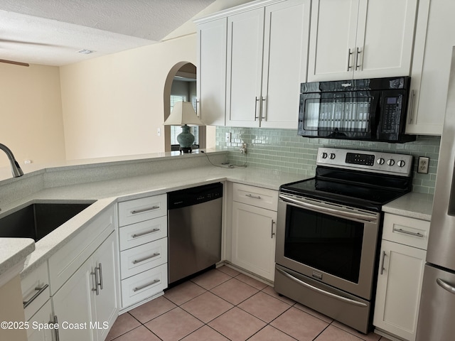 kitchen featuring sink, light tile patterned floors, stainless steel appliances, decorative backsplash, and white cabinets